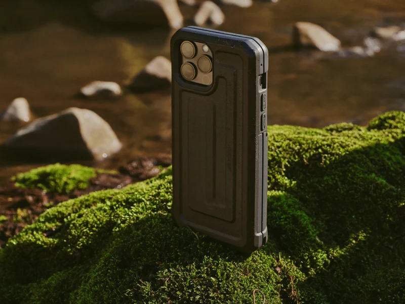 Smartphone in robuster Hülle auf bemoostem Fels an einem feuchten Wanderweg